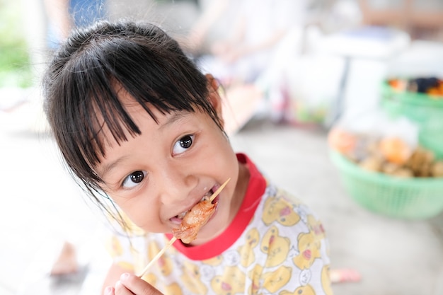 Menina gosta de comer carne de porco grelhada