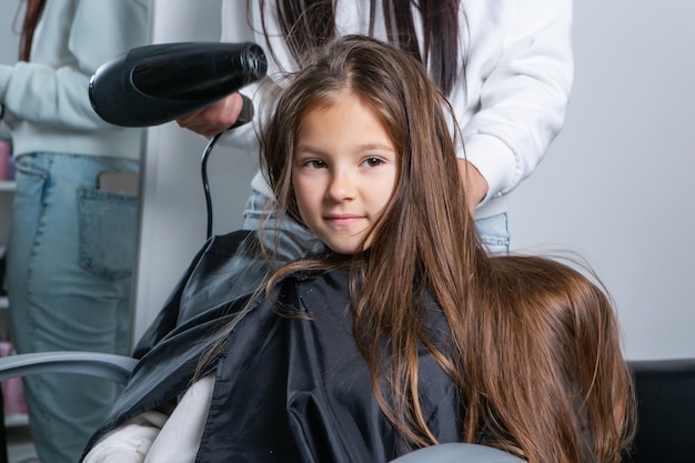 Menina gostando de seu primeiro corte de cabelo em um salão de beleza
