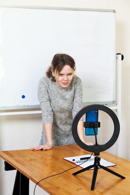 Menina gravando vídeo no smartphone e se acendendo com uma lâmpada circular