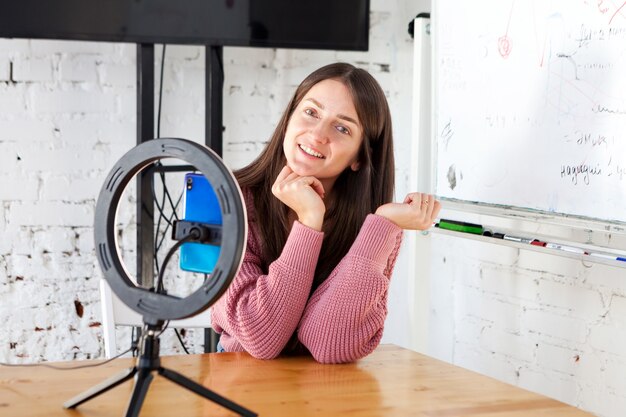 Menina gravando vídeo no smartphone e se iluminando com uma lâmpada circular