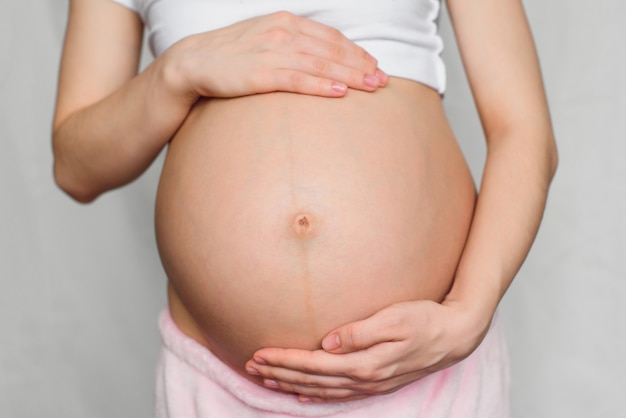 Menina grávida abraçando gentilmente a barriga