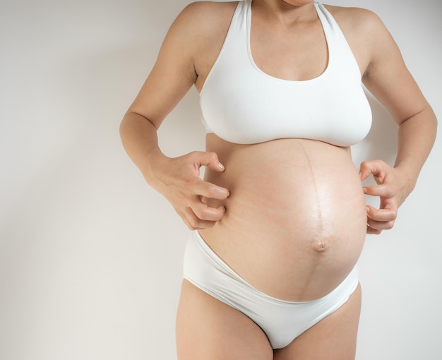 Foto menina grávida coçando a barriga prurido durante a gravidez sintomas de distúrbios metabólicos ou cert ...