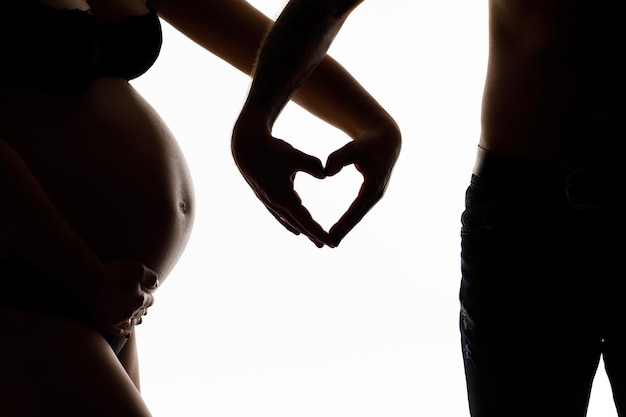 Menina grávida com namorado faz coração com mãos conceito de gravidez