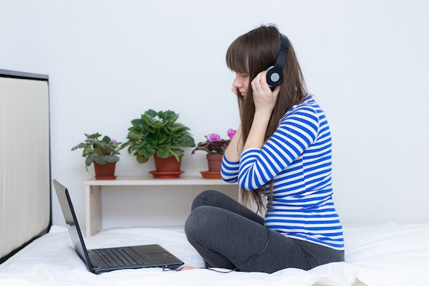 Menina grávida com um laptop na cama.