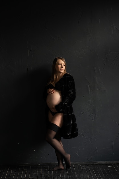 menina grávida contra uma parede preta