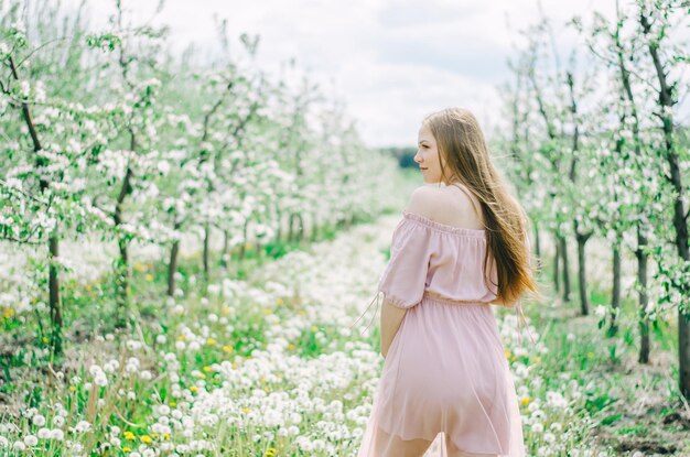 Menina grávida em um vestido rosa em um jardim de flores