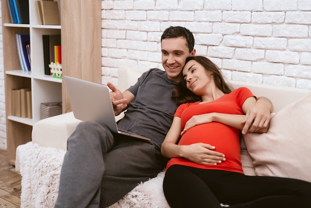 Foto menina grávida está sentado com um homem e assistindo algo.