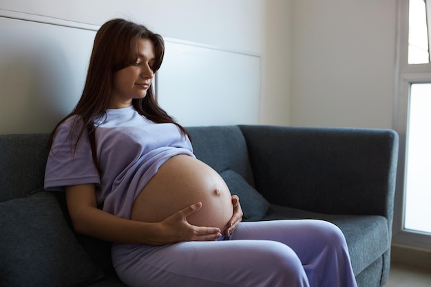 Foto menina grávida sentada no sofá na espaçosa sala de reuniões