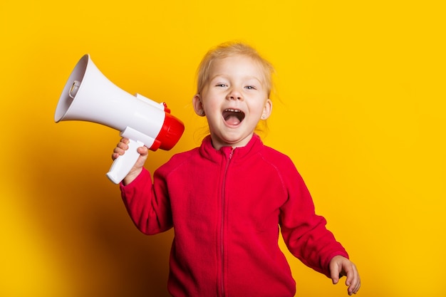 Menina grita segurando um megafone em um fundo amarelo brilhante.