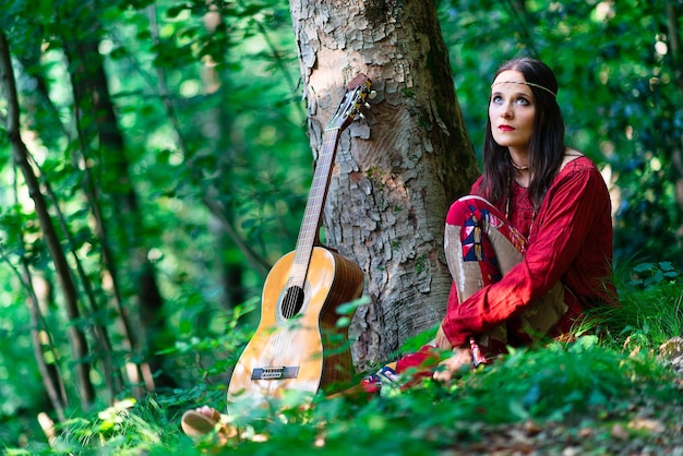 Menina hippie com o violão na floresta