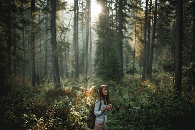 Menina hippie segurando caneca na floresta