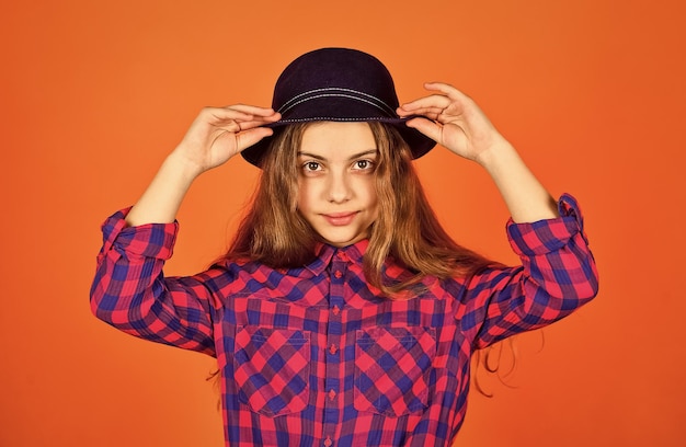 Menina hipster usa chapéu retrô elegante garoto olhando moda xadrez retrô para adolescente conceito de infância feliz menina pequena segue as últimas tendências beleza pura e natural criança tem cabelo comprido