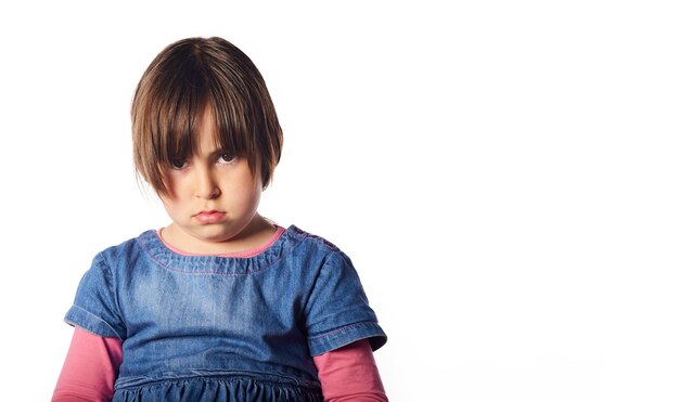 Foto menina hispânica de 5 anos, olhando para a câmera com um gesto de raiva. fundo branco e grande copyspace para marketing e publicidade.