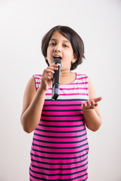 Foto menina indiana bonitinha cantando no microfone, isolada sobre um fundo branco