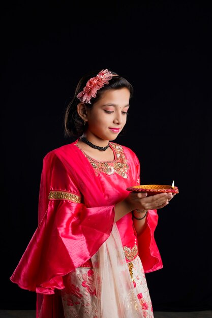 Menina indiana bonitinha segurando diya ou lâmpadas de óleo para a celebração de Diwali.