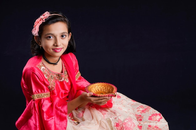 Menina indiana bonitinha segurando diya ou lâmpadas de óleo para a celebração de Diwali.