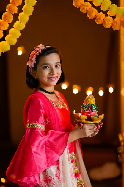 Menina indiana bonitinha segurando diya ou lâmpadas de óleo para a celebração de diwali.