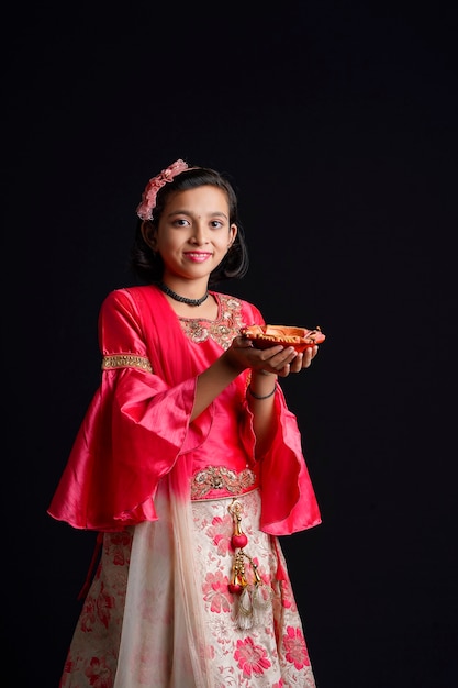 Menina indiana bonitinha segurando diya ou lâmpadas de óleo para a celebração de Diwali.