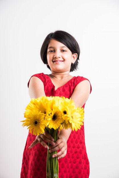 Menina indiana bonitinha segurando um ramo ou buquê de flores frescas Gerbera amarela. Isolado sobre fundo branco