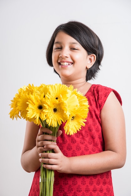 Menina indiana bonitinha segurando um ramo ou buquê de flores frescas gerbera amarela. isolado sobre fundo branco