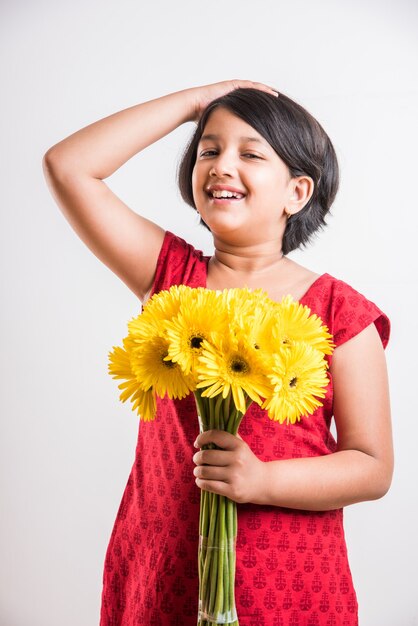 Menina indiana bonitinha segurando um ramo ou buquê de flores frescas gerbera amarela. isolado sobre fundo branco