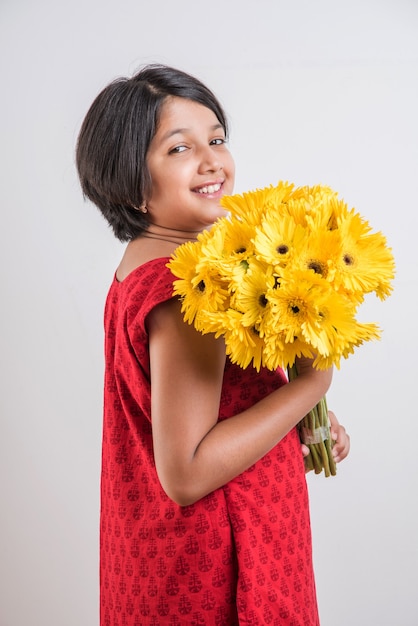 Menina indiana bonitinha segurando um ramo ou buquê de flores frescas gerbera amarela. isolado sobre fundo branco