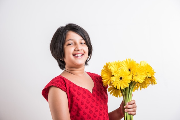 Menina indiana bonitinha segurando um ramo ou buquê de flores frescas Gerbera amarela. Isolado sobre fundo branco