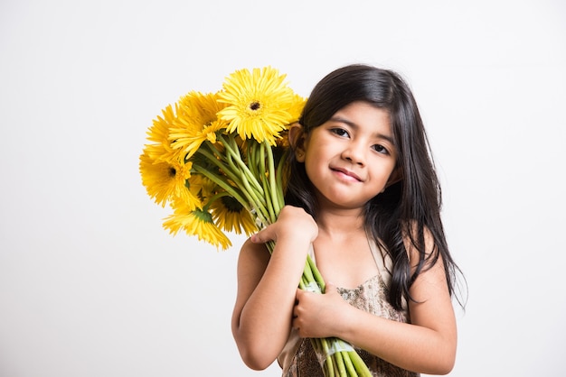 Menina indiana bonitinha segurando um ramo ou buquê de flores frescas gerbera amarela. isolado sobre fundo branco