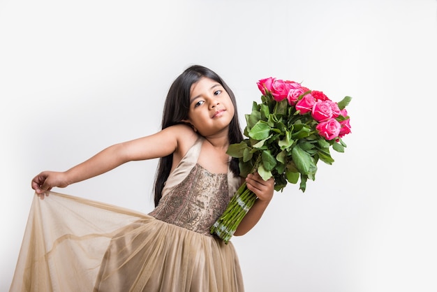 Menina indiana bonitinha segurando um ramo ou buquê de rosas vermelhas frescas ou flores de Gulab. Isolado sobre fundo branco