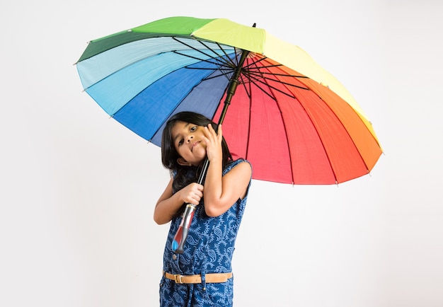 Menina indiana com guarda-chuva multicolorido, isolada sobre o branco