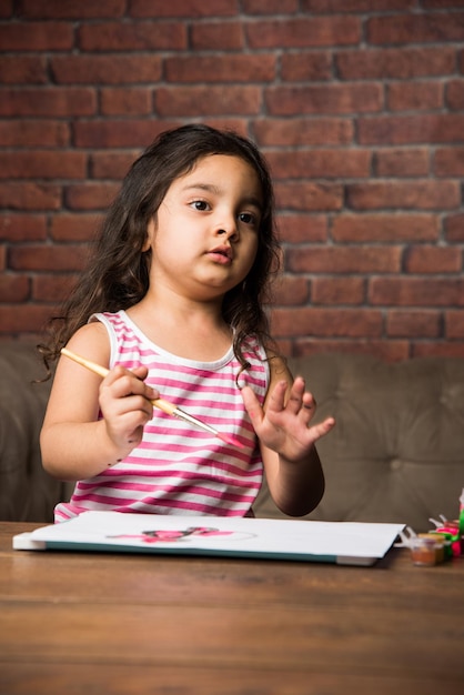 Menina indiana desenhando ou pintando com cores sobre papel, foco seletivo