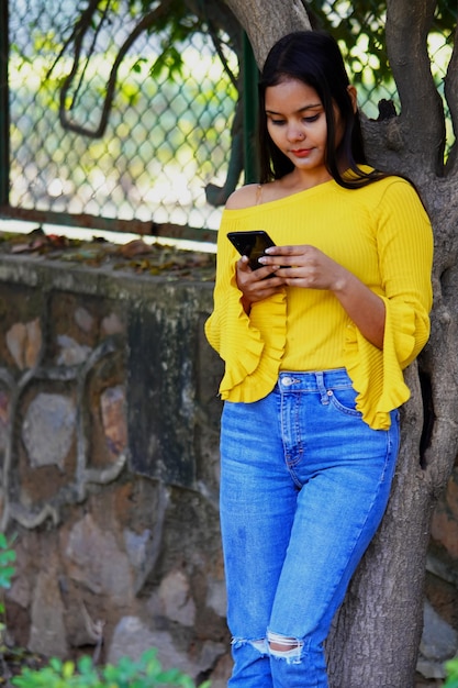 Menina indiana em pé e usando telefone celular