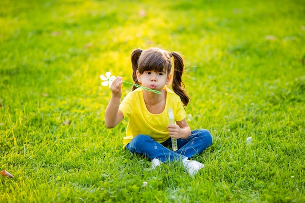 Menina indiana fofa de verão no gramado soprando bolhas de sabão