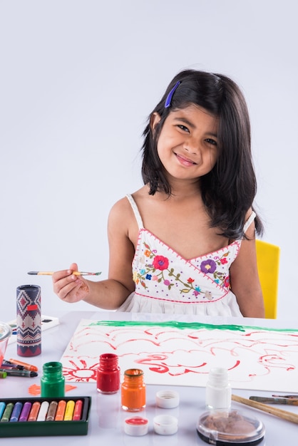 Menina indiana ou asiática bonitinha apreciando a pintura em casa com papel, cor de água e pincel de arte. Foco seletivo