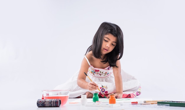 Menina indiana ou asiática bonitinha apreciando a pintura em casa com papel, cor de água e pincel de arte. Foco seletivo