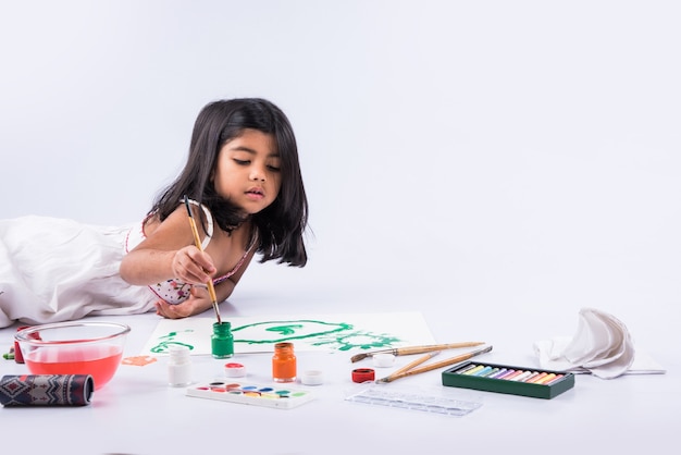 Menina indiana ou asiática bonitinha apreciando a pintura em casa com papel, cor de água e pincel de arte. Foco seletivo