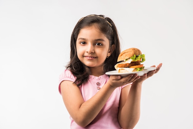 Menina indiana ou asiática bonitinha comendo hambúrguer no fundo branco