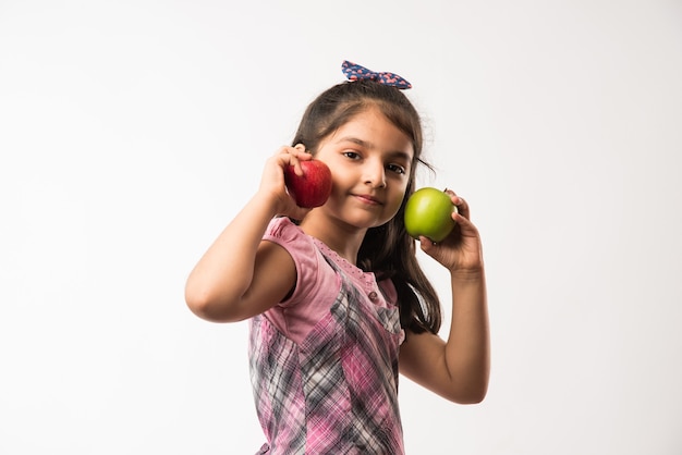 Menina indiana ou asiática bonitinha segurando maçã verde e vermelha - conceito de alimentação saudável