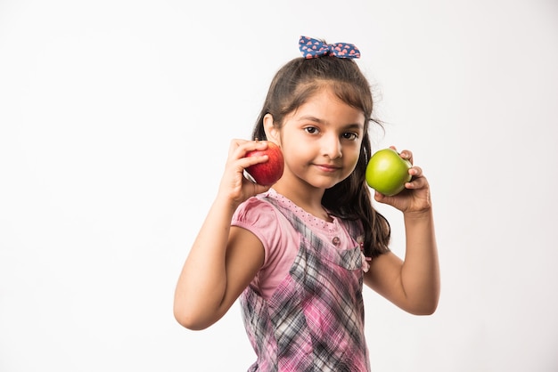 Menina indiana ou asiática bonitinha segurando maçã verde e vermelha - conceito de alimentação saudável