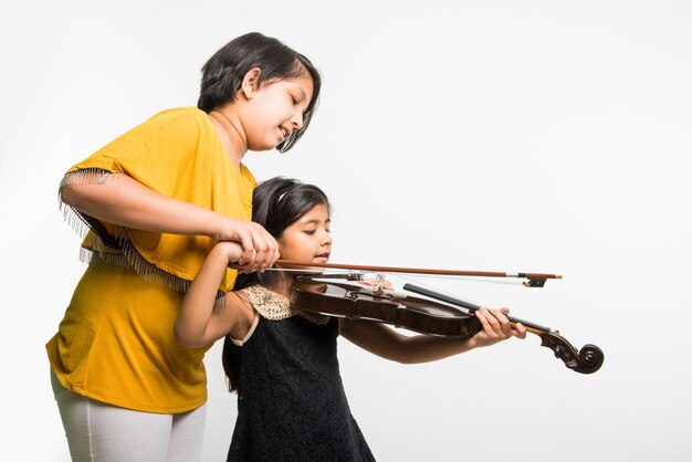 Menina indiana ou asiática bonitinha tocando violino, isolada sobre fundo branco