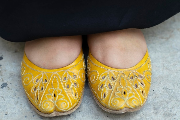 Foto menina indiana paquistanesa mostrando nossos sapatos com pés de vestido muçulmano abaya em sapatos no chão