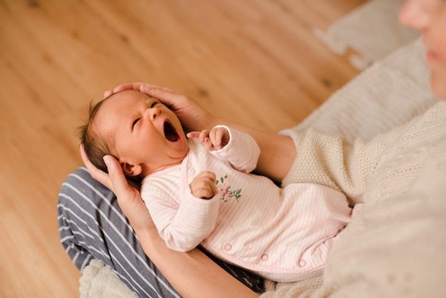 Menina infantil bonitinha bocejando e acordando nas mãos da mãe no quarto em casa perto da vista superior