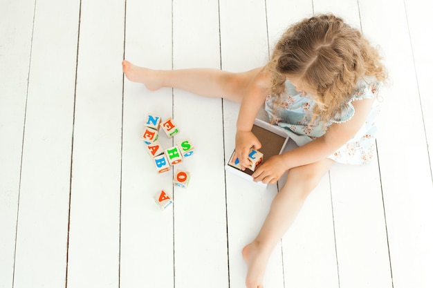 Menina irreconhecível brincando com cubos abc dentro de casa