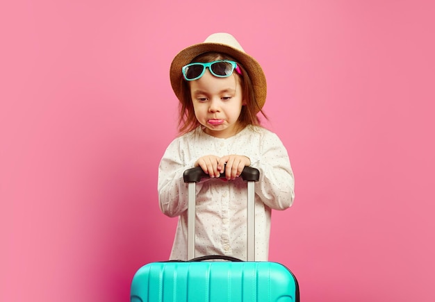 Menina irritada e triste com mala fica em rosa isolado. tristeza