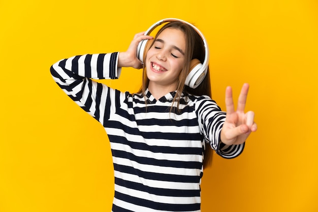 Menina isolada em um fundo amarelo ouvindo música e cantando