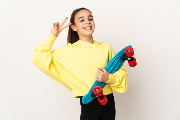 Menina isolada no fundo branco com um skate e uma expressão feliz