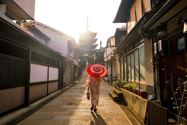 Menina japonesa em Yukata com guarda-chuva vermelho na cidade velha de Kyoto, Japão