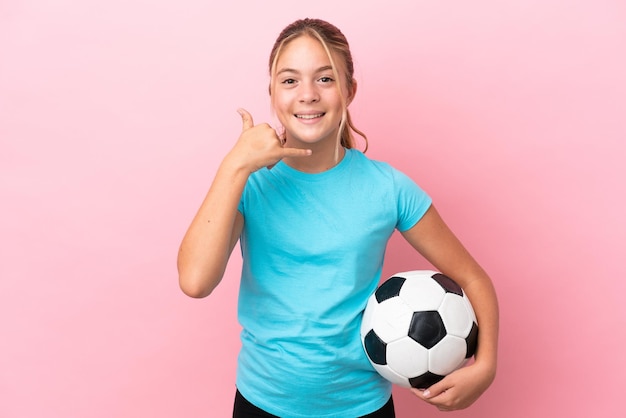 Menina jogador de futebol isolada no fundo rosa, fazendo gesto de telefone. Ligue-me de volta sinal