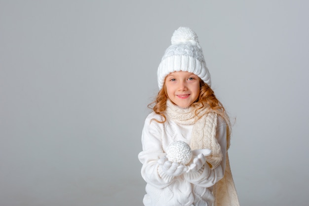 Menina jogando bola de neve com um chapéu em um fundo branco