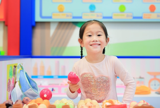 Menina jogando fingir como uma venda na sorveteria